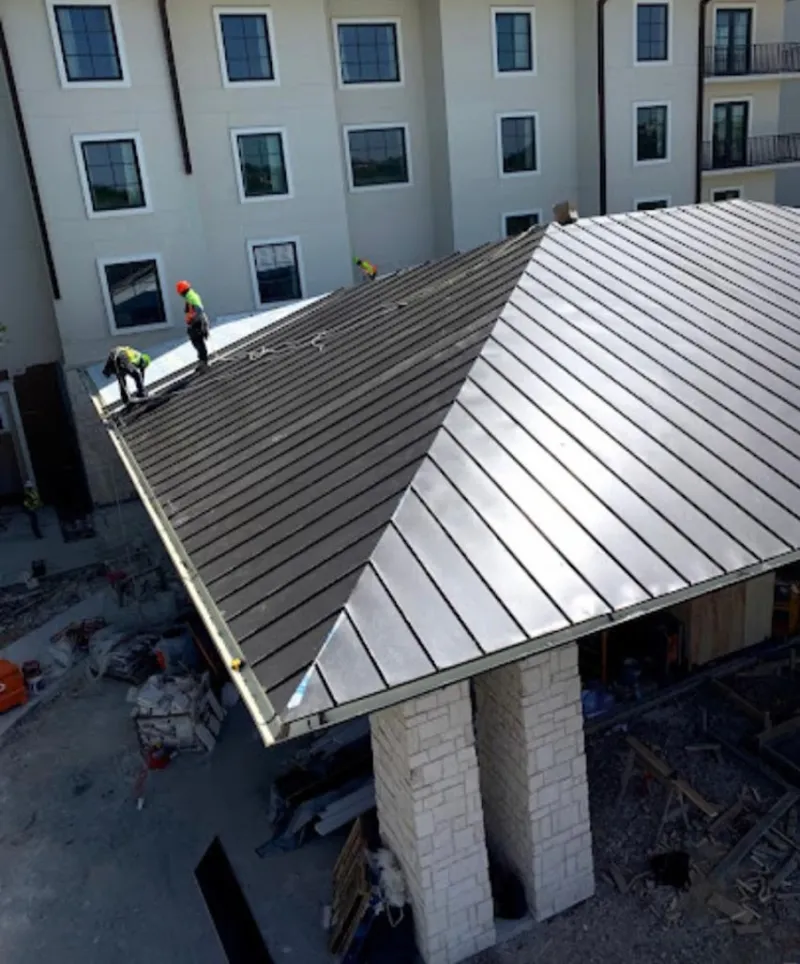 Crew installing standing seam metal roof panels on a commercial project in Cromwell